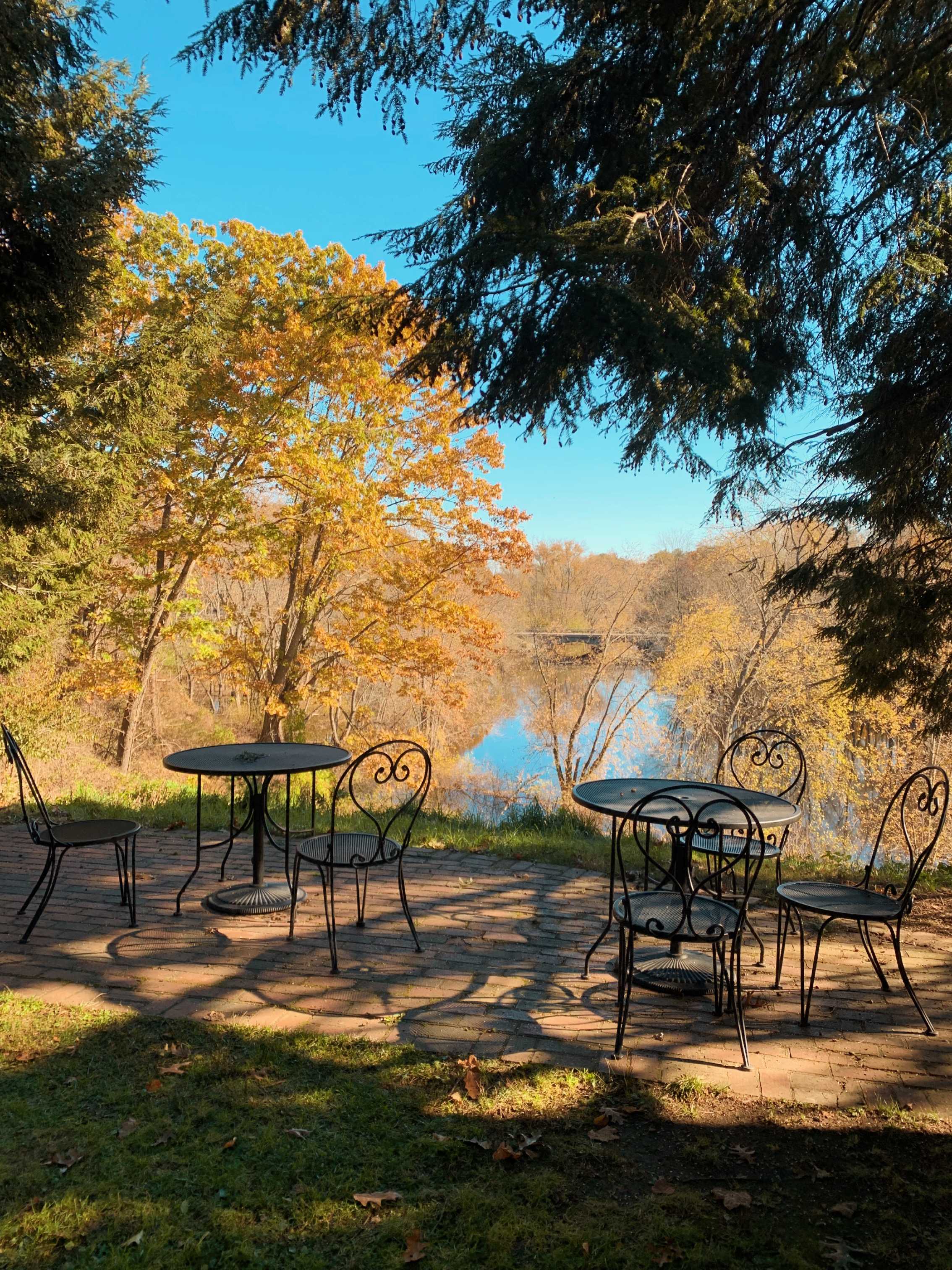 empty tables and chairs next to fall foliage